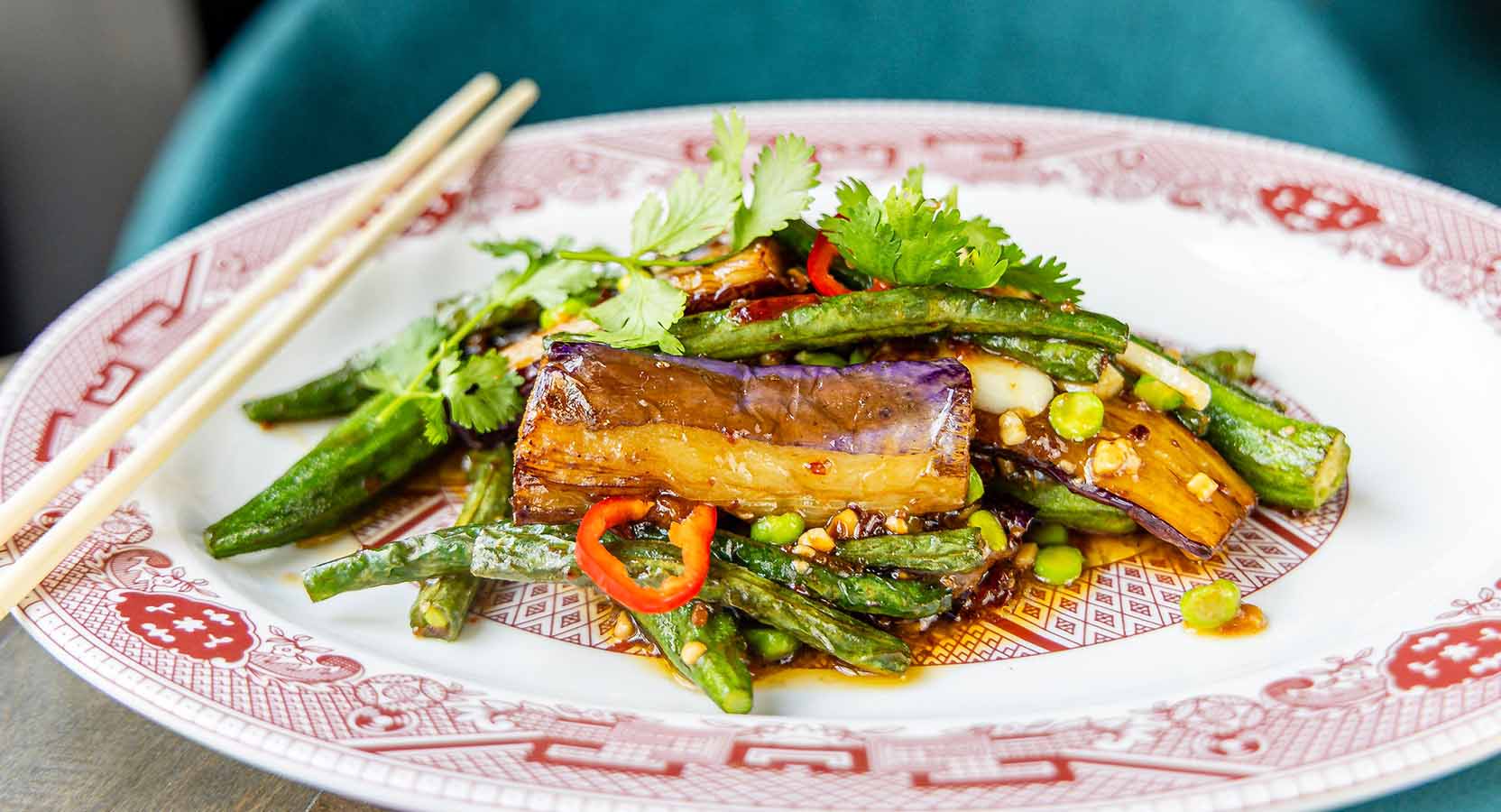 Stir-fried eggplant and green beans in garlic soy sauce with sliced red chili and cilantro.