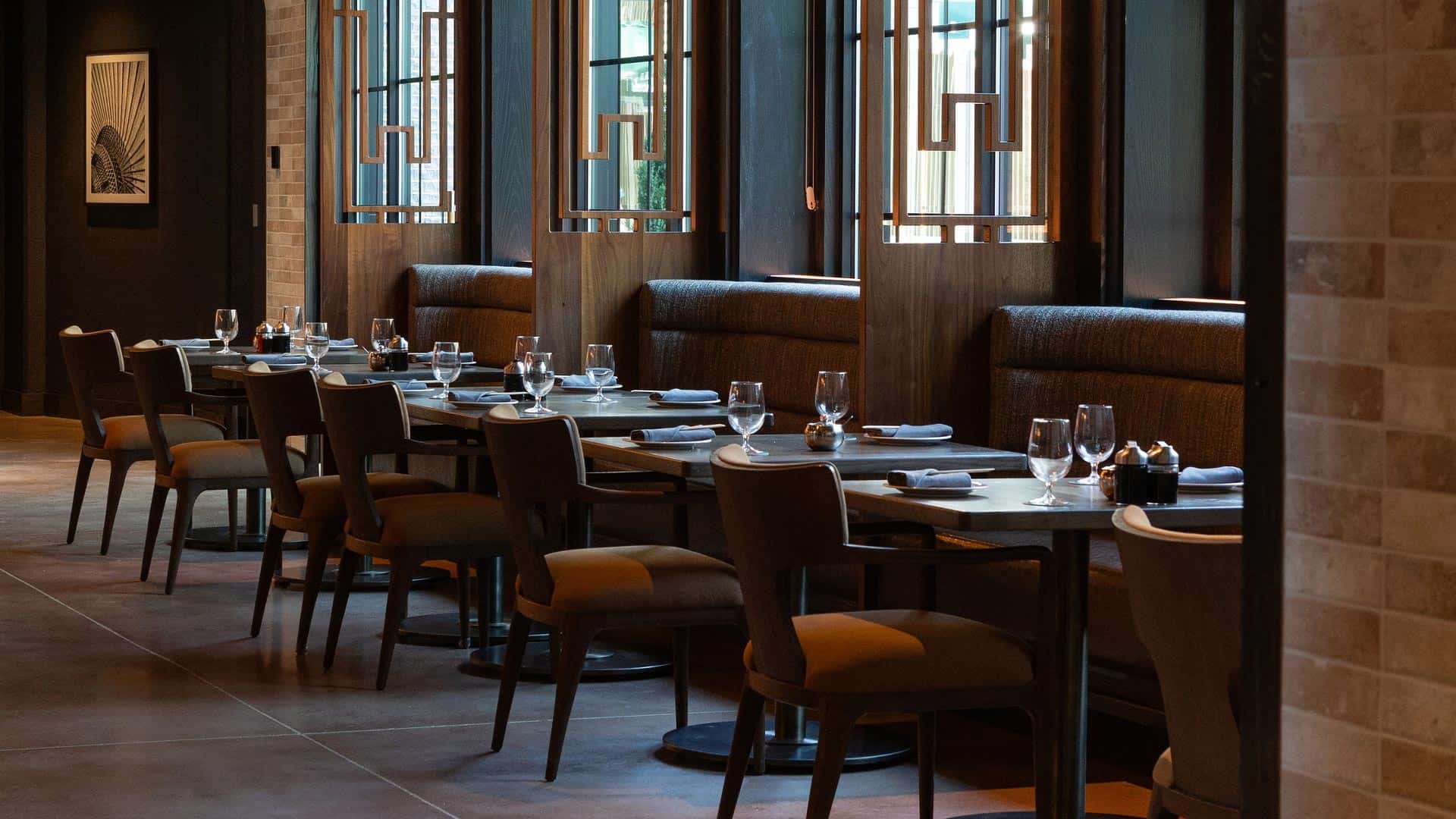 Elegant restaurant dining area with wood accents, cozy booth seating, and neatly set tables featuring wine glasses and napkins, perfect for a sophisticated dining experience.